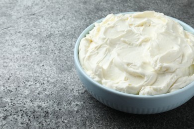 Bowl of tasty cream cheese on grey table. Space for text