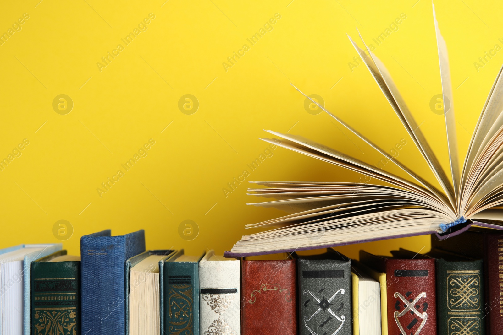 Photo of Collection of old books on yellow background, space for text