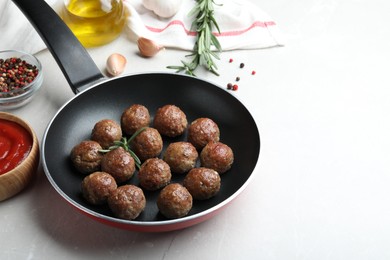 Photo of Tasty cooked meatballs on light marble table. Space for text