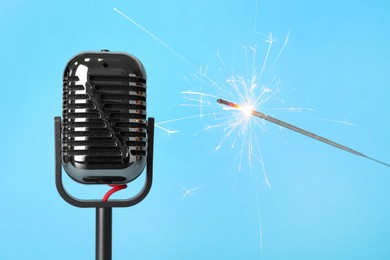 Photo of Making ASMR sounds with microphone and burning sparkler on light blue background, closeup