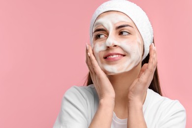 Photo of Young woman with headband washing her face on pink background, space for text