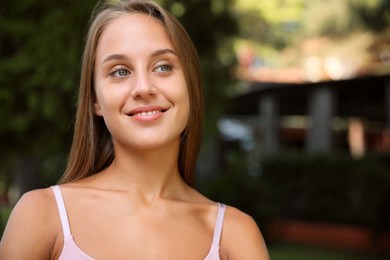 Portrait of beautiful young woman in park, space for text