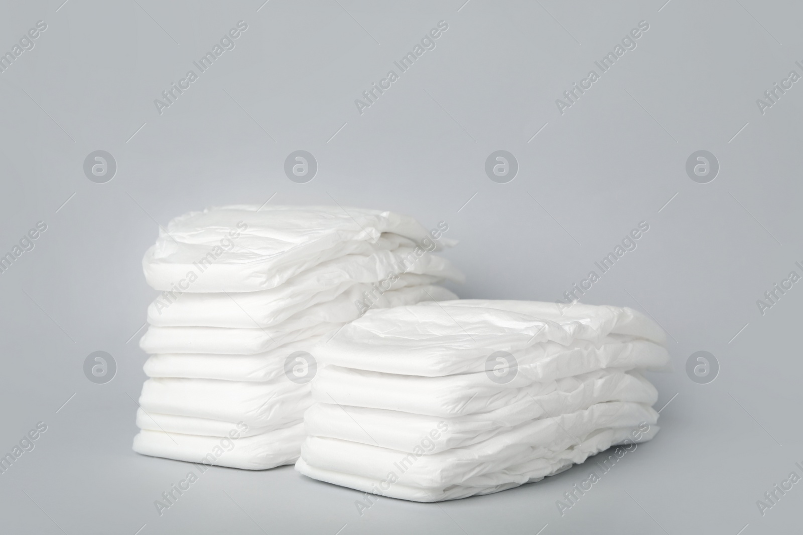 Photo of Stacks of diapers on light grey background