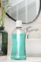 Photo of Bottle of mouthwash on white table in bathroom