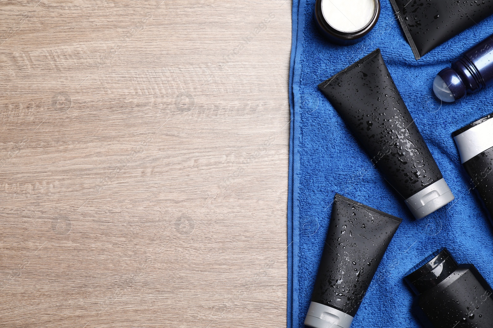 Photo of Set of men's cosmetic products with blue towel on wooden table, top view. Space for text