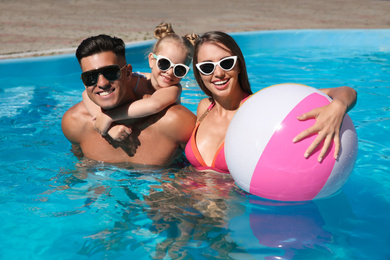 Photo of Happy family with inflatable ball in outdoor swimming pool on sunny summer day