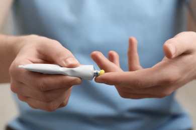 Photo of Man applying yellow ointment from tube onto his fingers, closeup