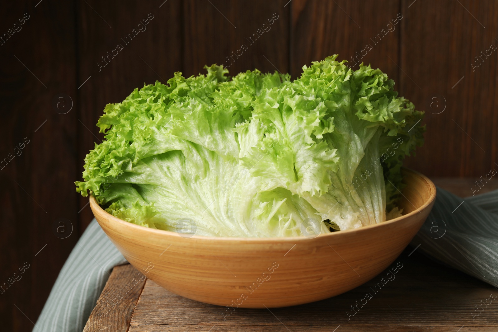 Photo of Fresh lettuce on wooden table. Salad greens