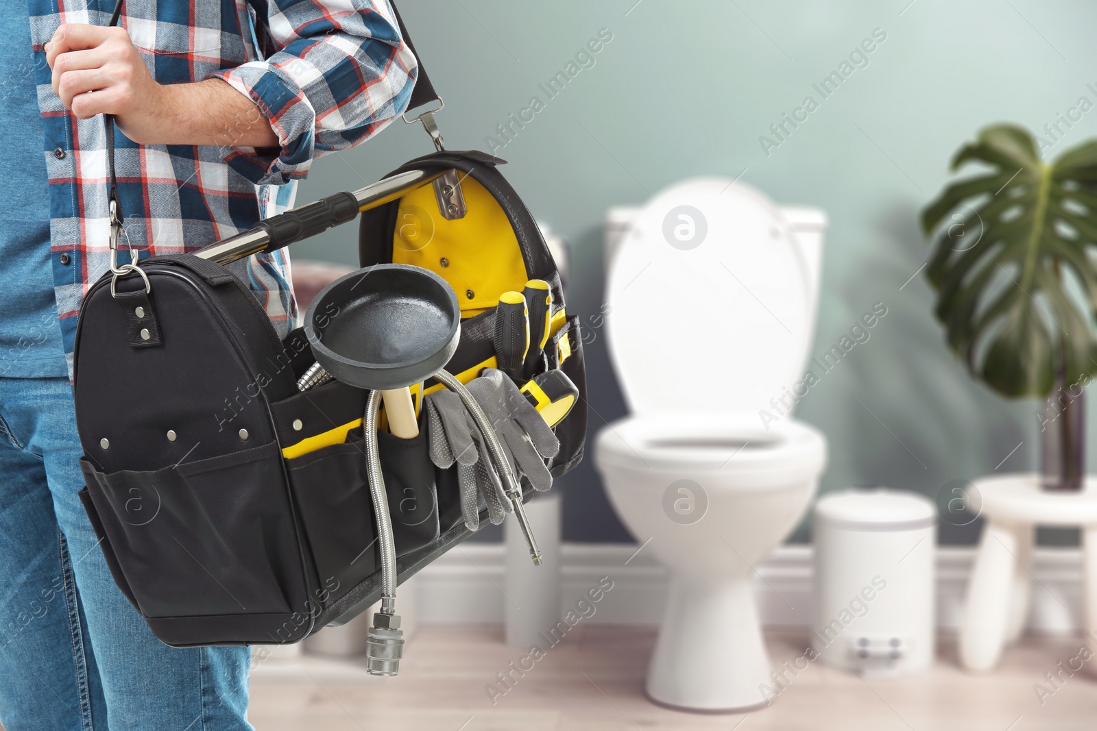 Image of Plumber with bag of instruments in bathroom, closeup. Space for text