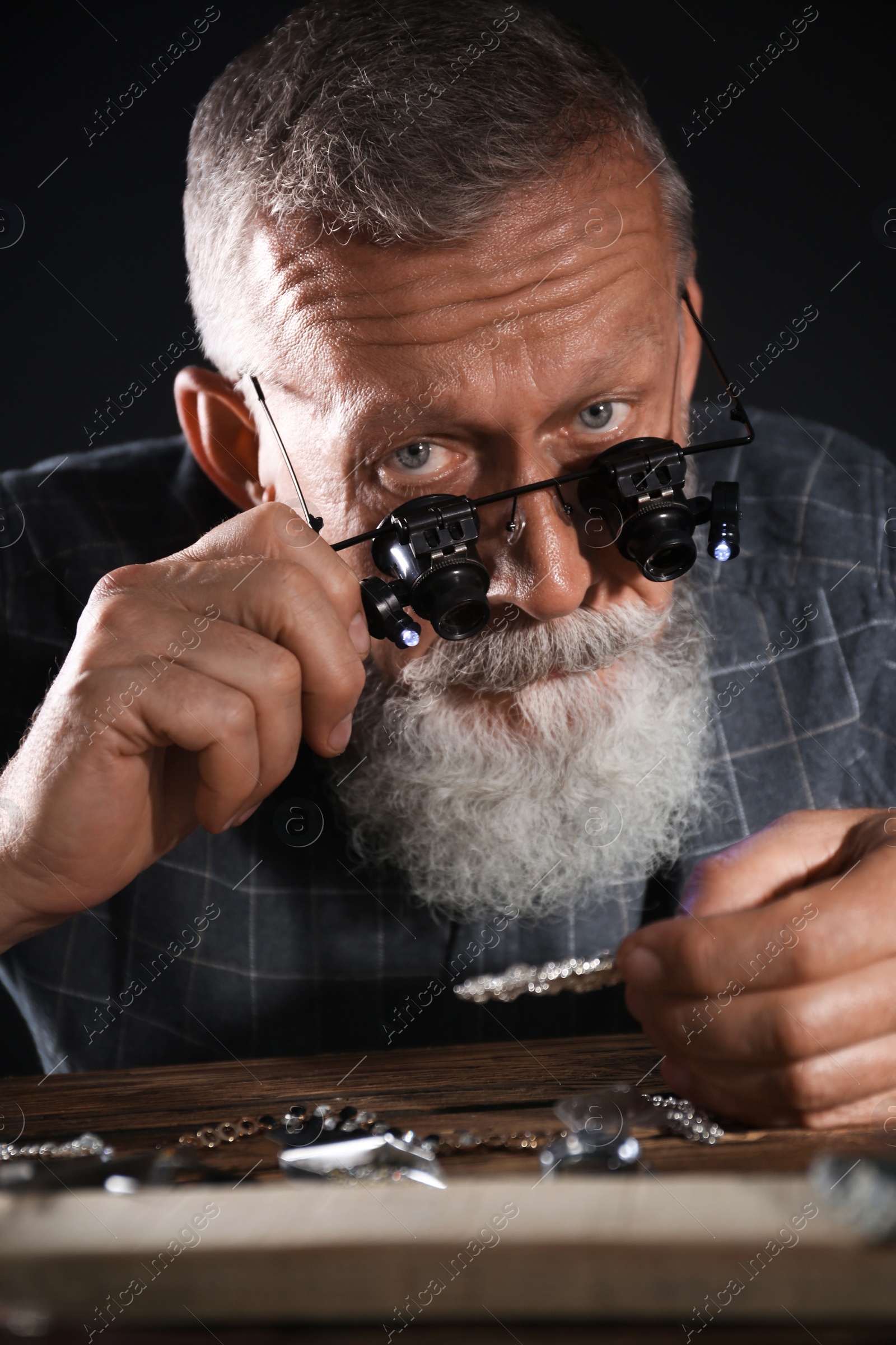 Photo of Male jeweler evaluating diamond brooch in workshop