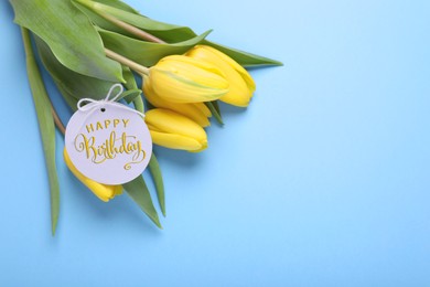 Image of Beautiful tulip flowers with Happy Birthday card on light blue background, space for text