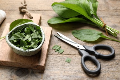 Photo of Broadleaf plantain leaves and scissors on wooden table