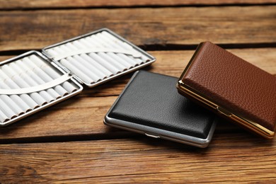 Photo of Stylish leather cigarette cases on wooden table