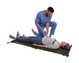 Photo of Doctor in uniform fixing woman on stretcher 
against white background. First aid