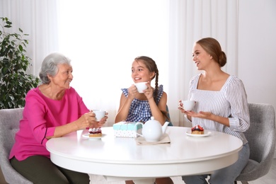 Photo of Beautiful mature woman, her daughter and grandchild having tea at home. Happy Mother's Day