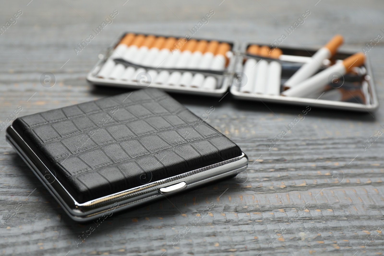 Photo of Stylish leather cigarette case on grey wooden table, closeup. Space for text