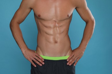 Shirtless man with slim body on light blue background, closeup