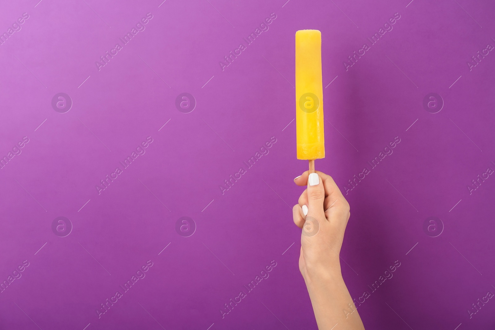 Photo of Woman holding yummy ice cream on color background. Focus on hand