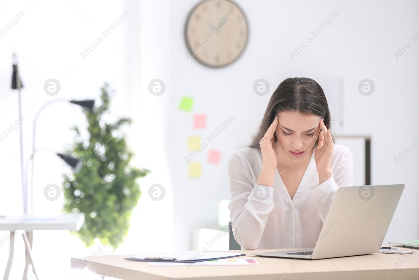 Photo of Young woman suffering from headache in office