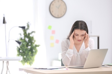 Young woman suffering from headache in office