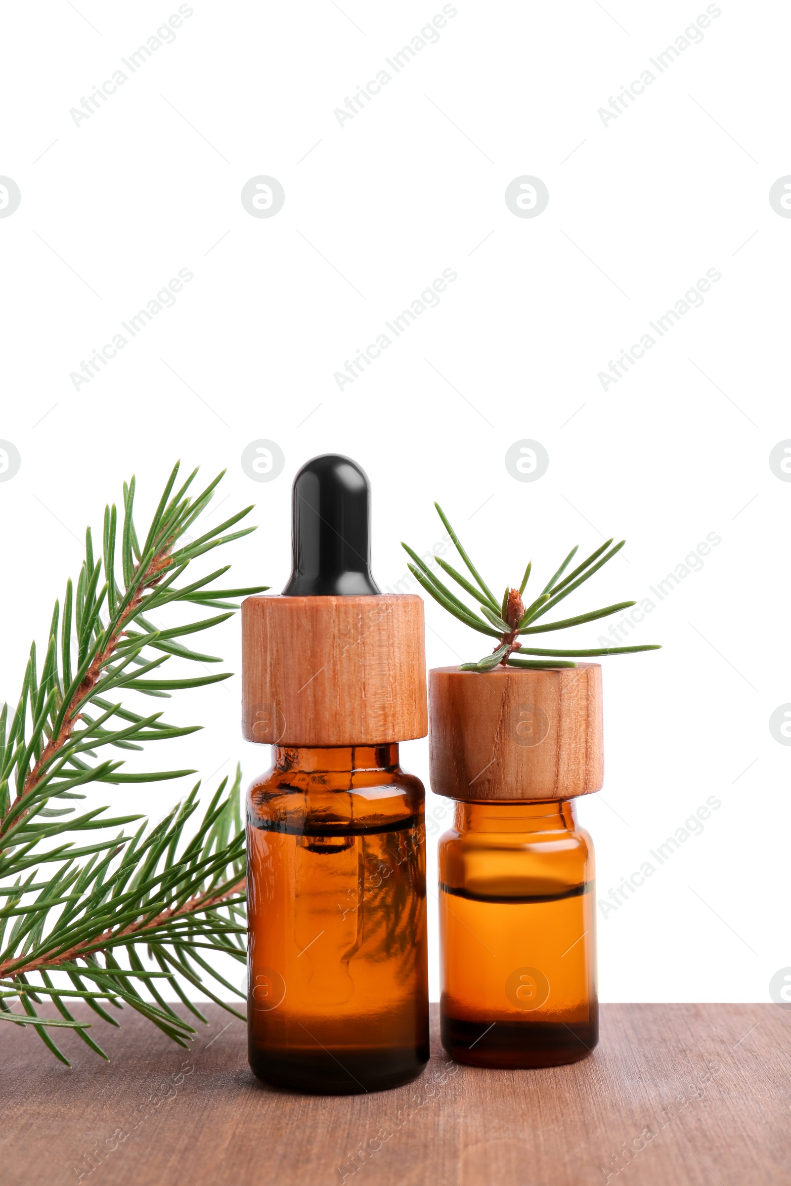 Photo of Bottles of pine essential oil and tree branch on wooden table against white background