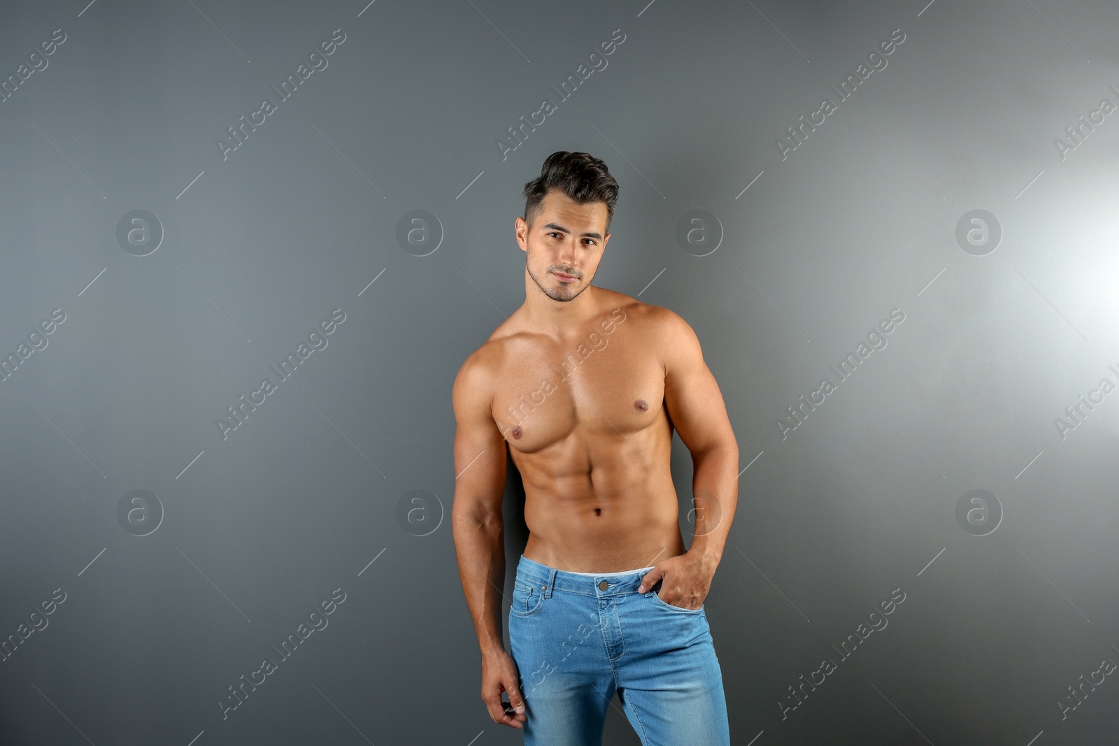 Photo of Shirtless young man in stylish jeans on grey background