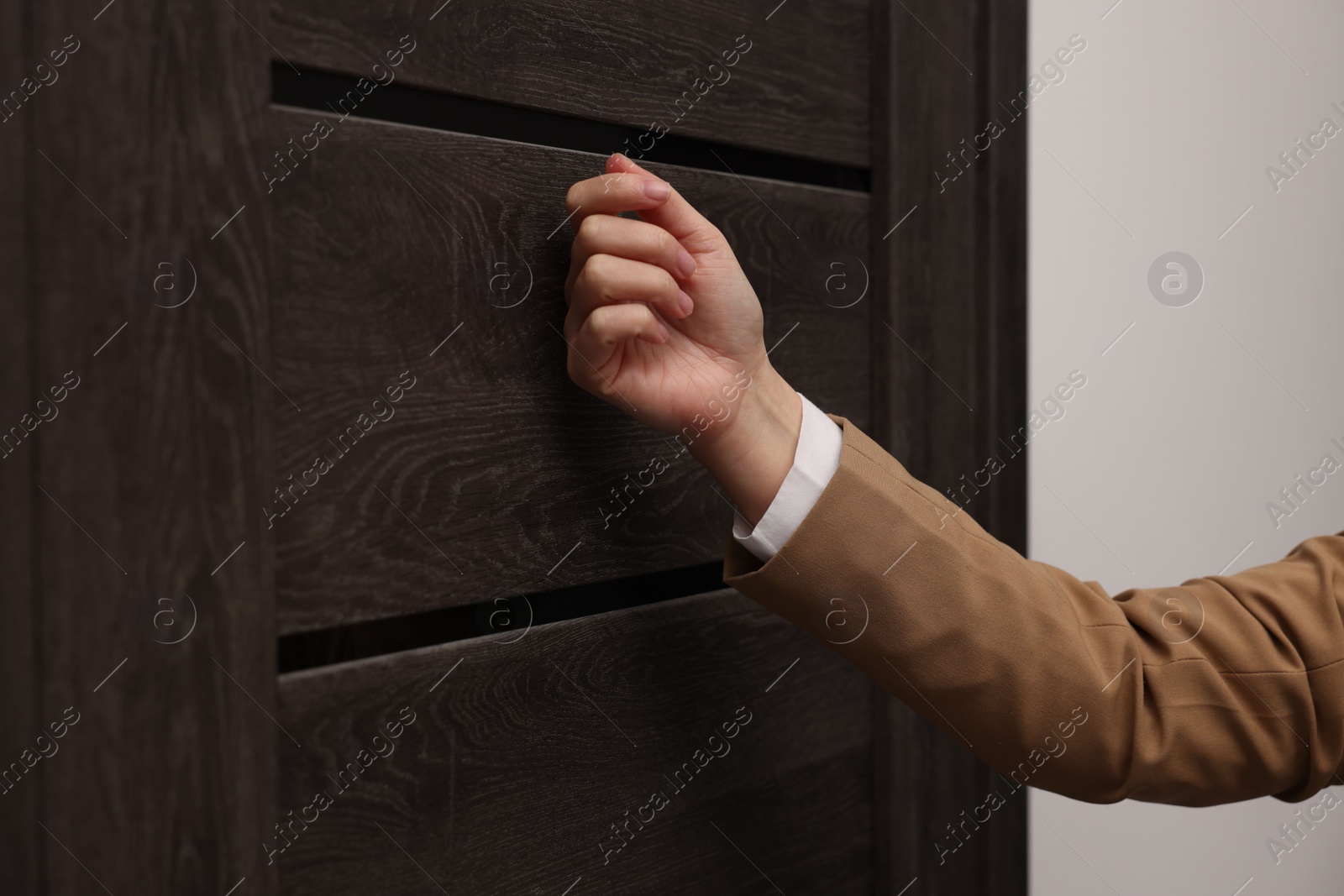 Photo of Collector knocking on door indoors, closeup view