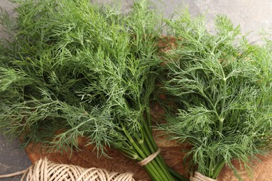 Photo of Bunches of fresh dill and spool of thread on grey table, flat lay