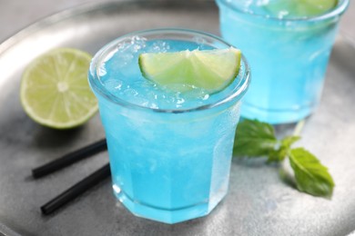 Photo of Tasty fresh light blue drink with lime on silver tray