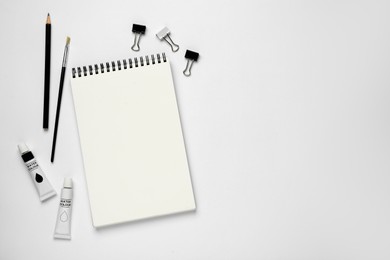 Composition with sketchbook and drawing tools on white background, top view. Space for text
