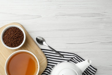 Buckwheat tea and granules on white wooden table, flat lay. Space for text