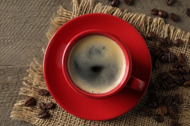 Photo of Cup of aromatic coffee and beans on wooden table, top view