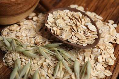 Photo of Spoon with oatmeal and florets on wooden table, closeup