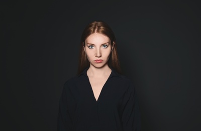 Portrait of young woman against dark background