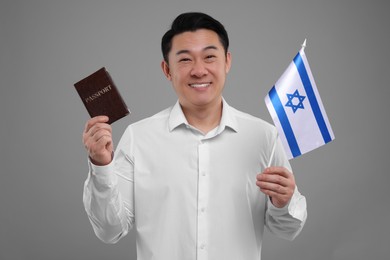 Immigration. Happy man with passport and flag of Israel on grey background