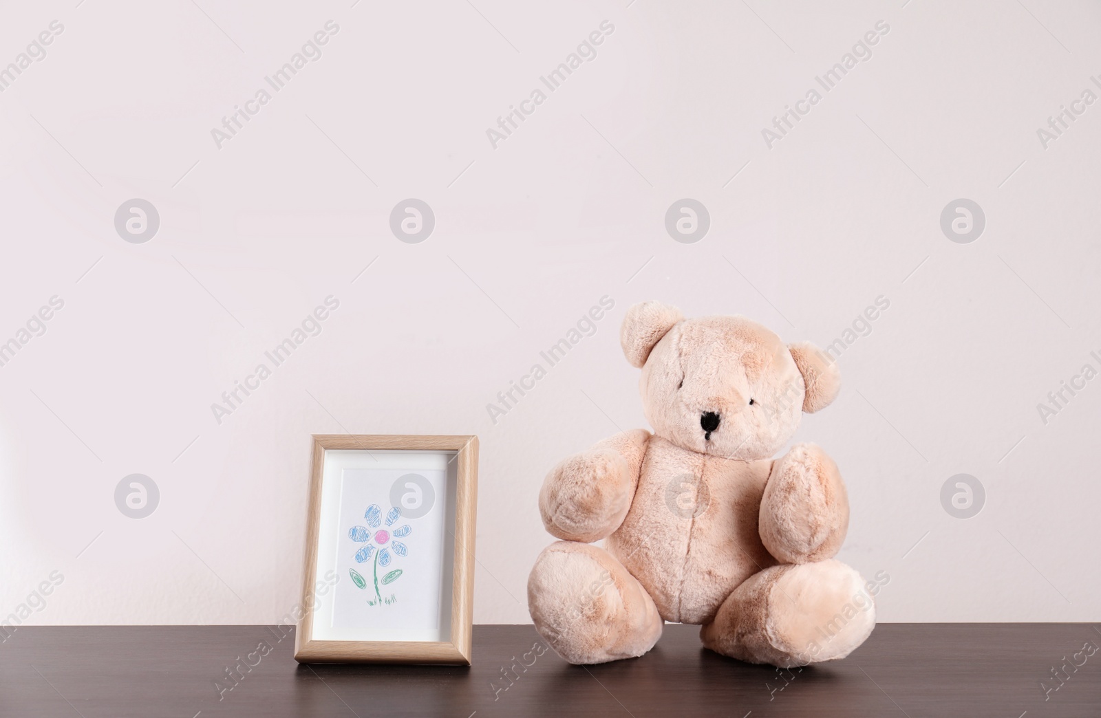 Photo of Adorable teddy bear and frame with cute picture on table against light background, space for text. Child room elements