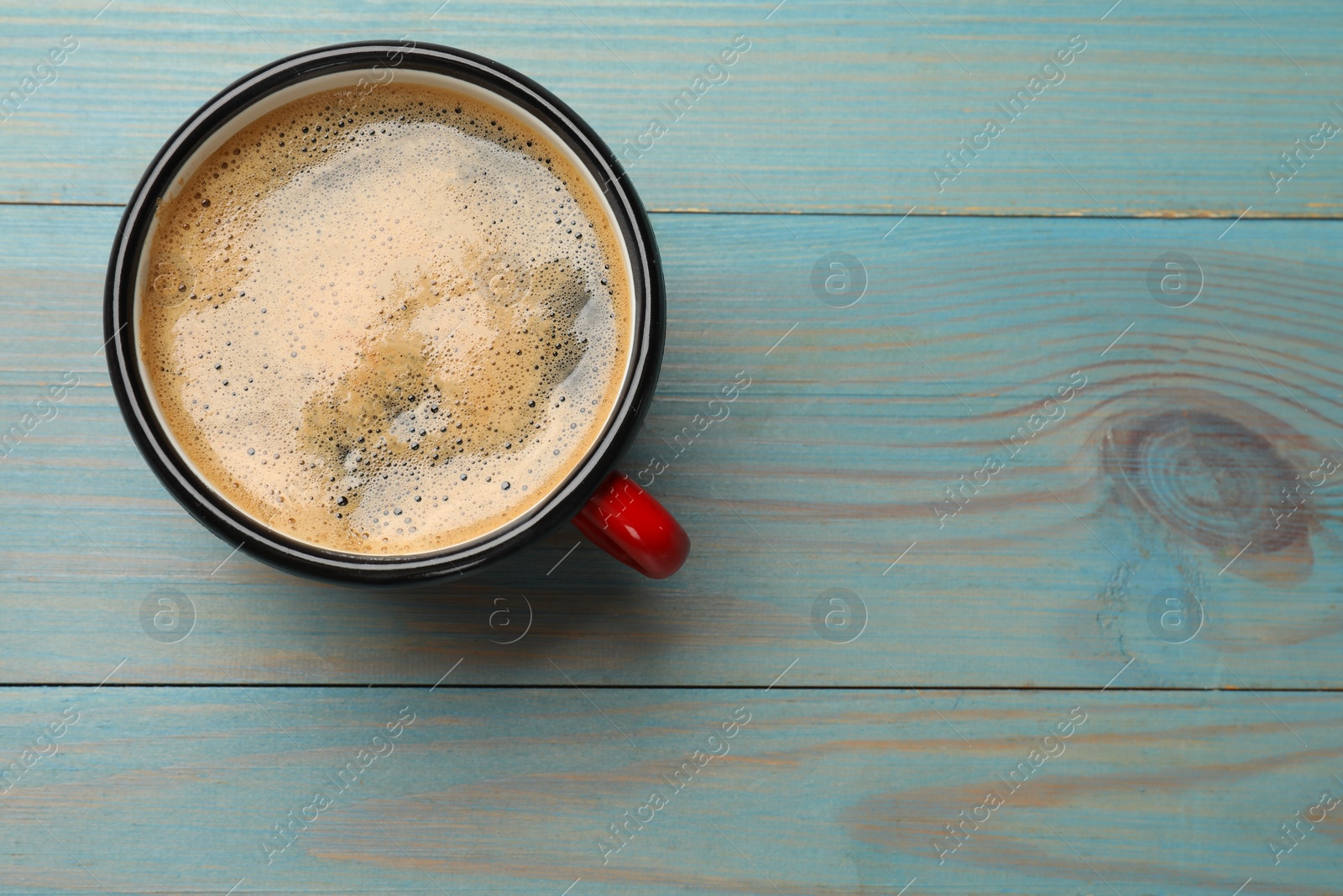 Photo of Cup of aromatic coffee on light blue wooden table, top view. Space for text