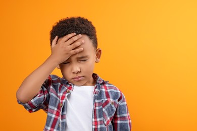 Photo of Portrait of emotional African-American boy on orange background. Space for text