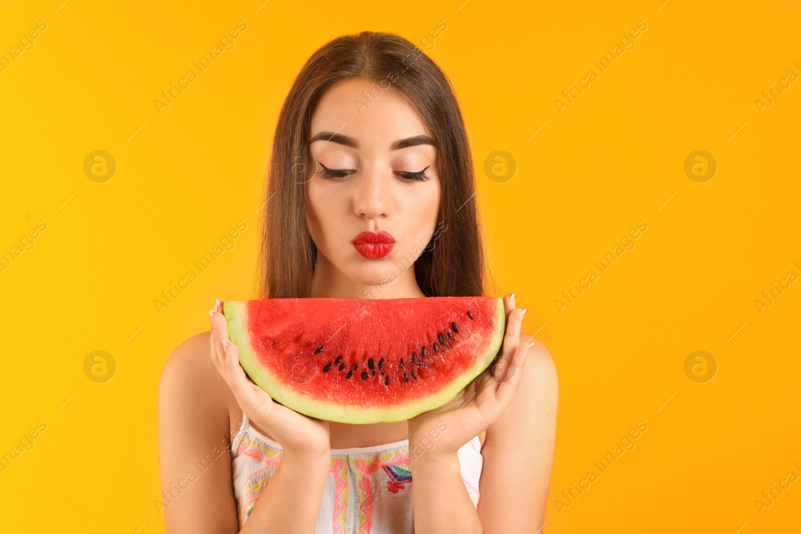 Photo of Beautiful young woman posing with watermelon on color background