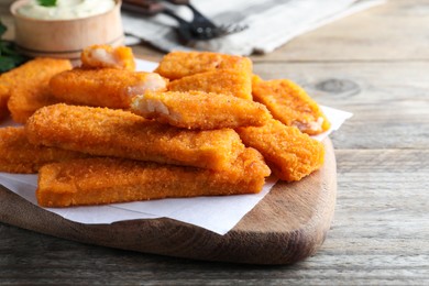 Photo of Tasty fresh fish fingers served on wooden table, space for text