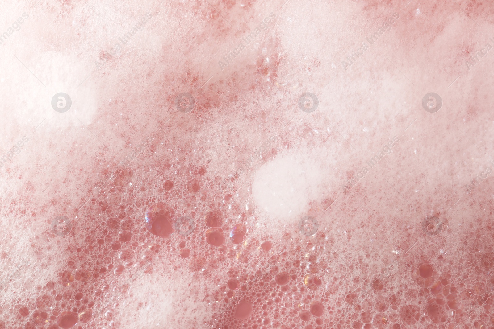 Photo of Fluffy bath foam on pink background, closeup