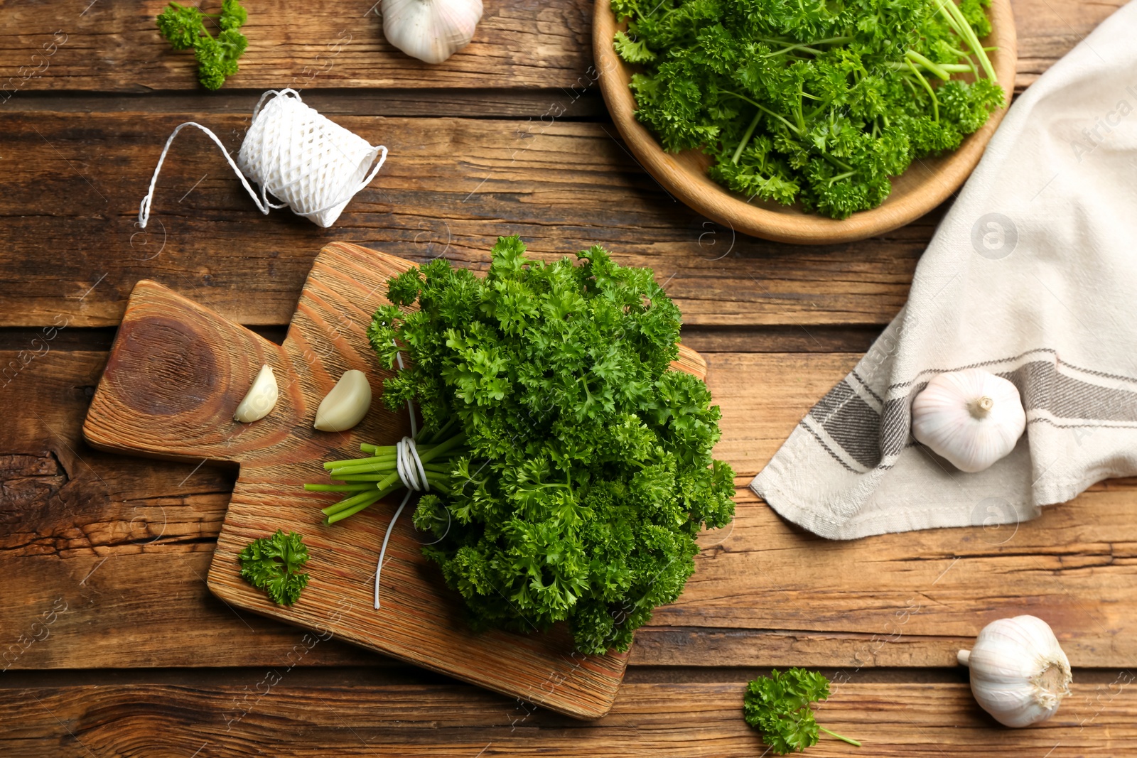 Photo of Fresh curly parsley and garlic on wooden table, flat lay