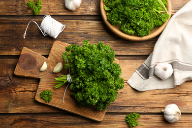 Fresh curly parsley and garlic on wooden table, flat lay