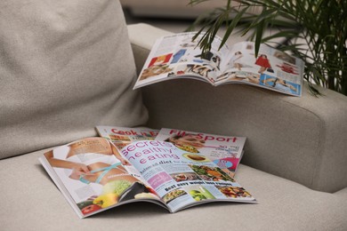 Photo of Different lifestyle magazines on comfortable sofa indoors