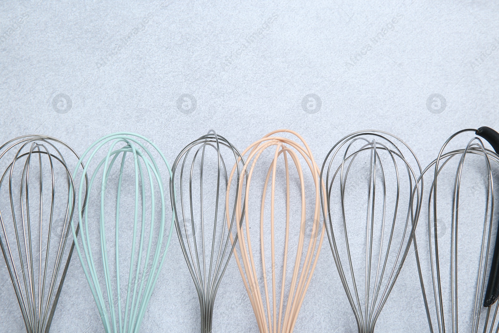 Photo of Different whisks on gray table, flat lay. Space for text