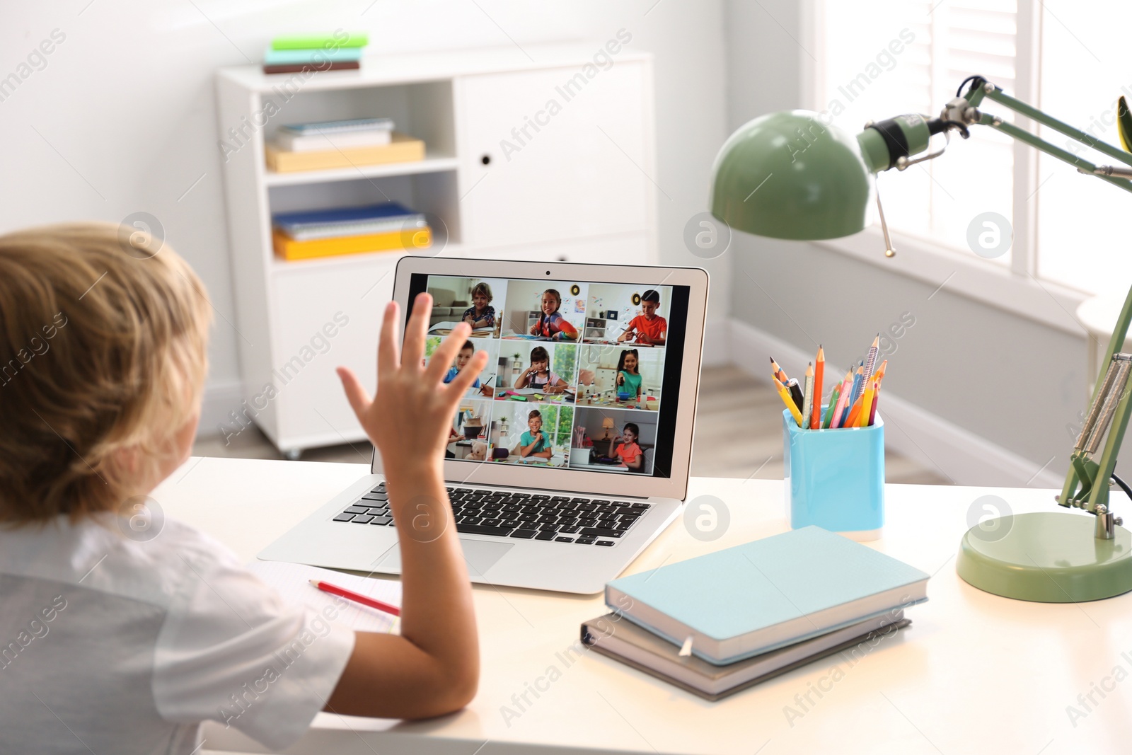 Photo of Little boy studying with classmates via video conference at home. Distance learning during COVID-19 pandemic