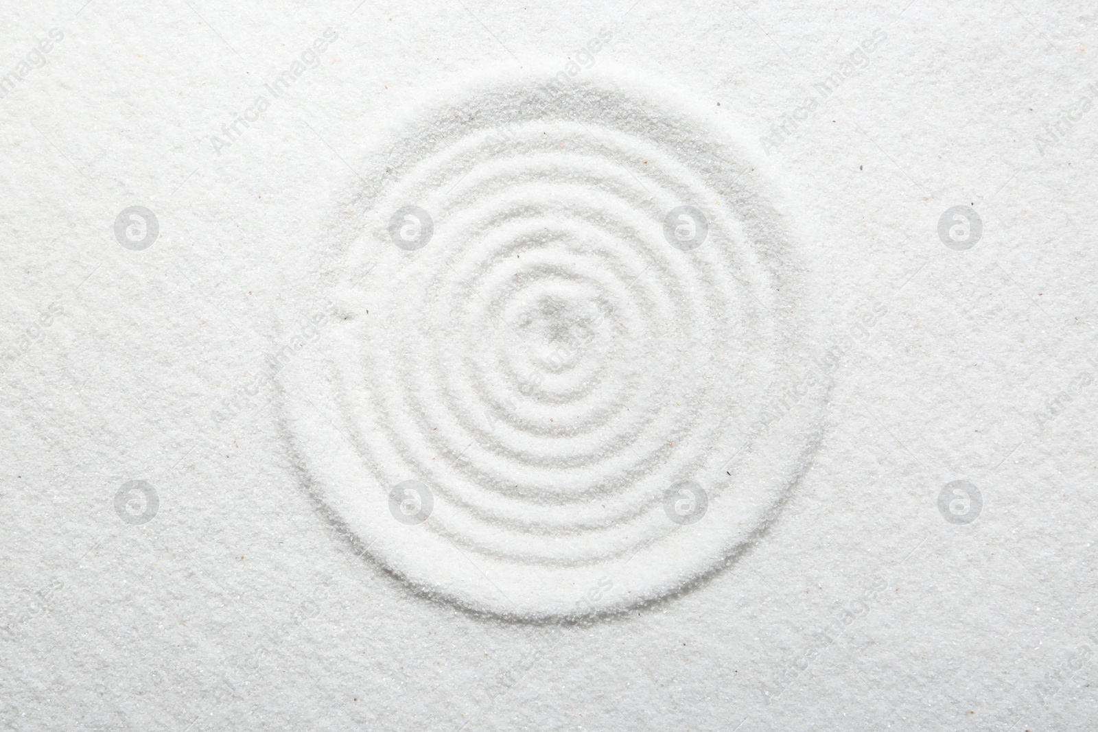 Photo of Zen rock garden. Circle pattern on white sand, top view