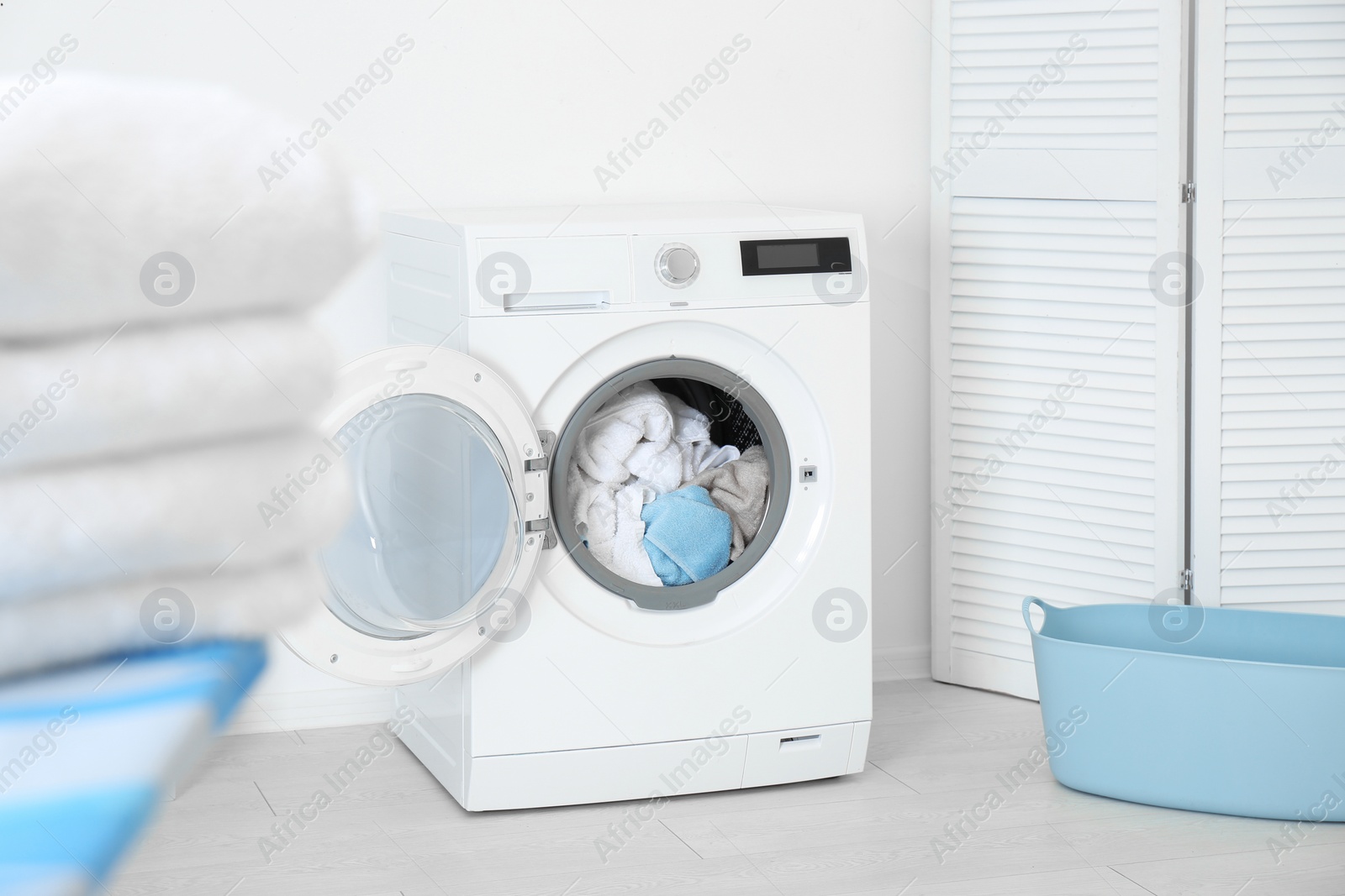 Photo of Washing machine with towels in modern laundry room