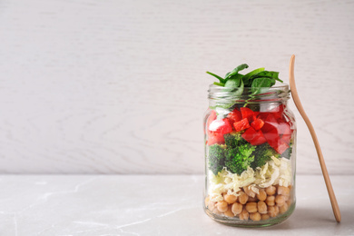 Photo of Healthy salad in glass jar on white table. Space for text