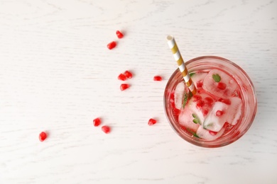 Photo of Tasty cocktail with pomegranate ice cubes and seeds on wooden background, top view. Space for text